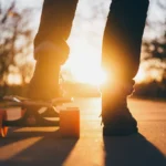 Skateboarder standing on a board in warm evening light
