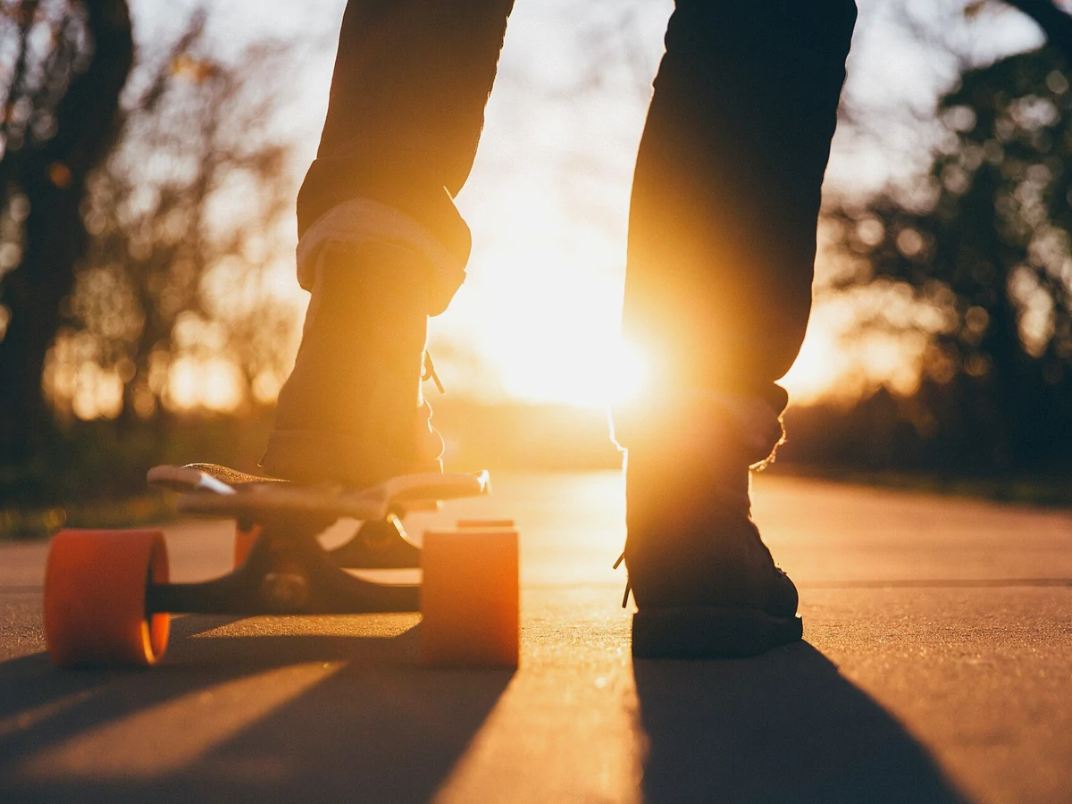 Skateboarder standing on a board in warm evening light