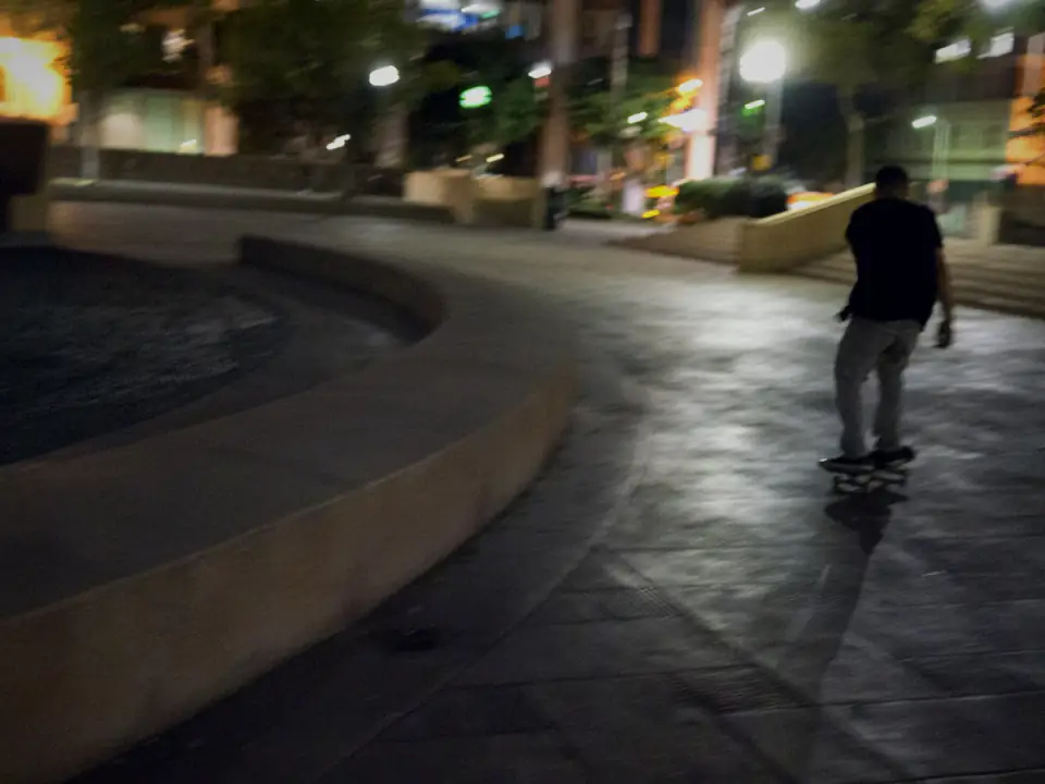 Skateboarder riding through a city at night