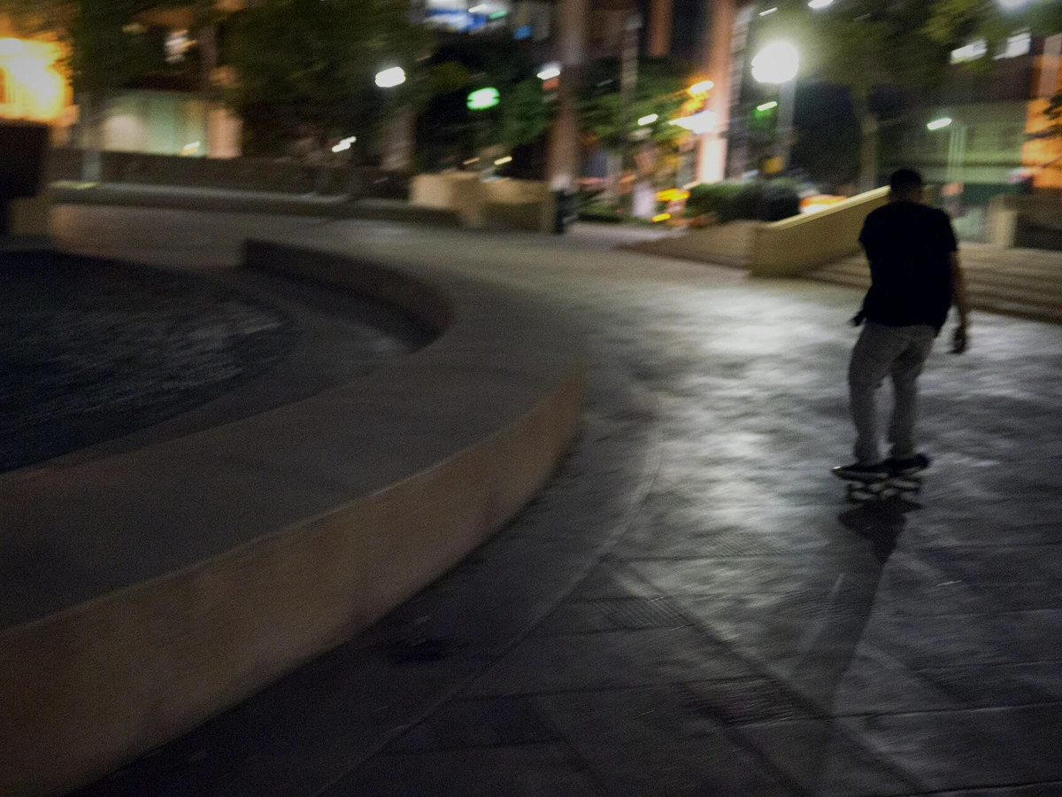 Skateboarder rolling through a city plaza at night