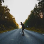 Skateboarder carving down an open road at sunset